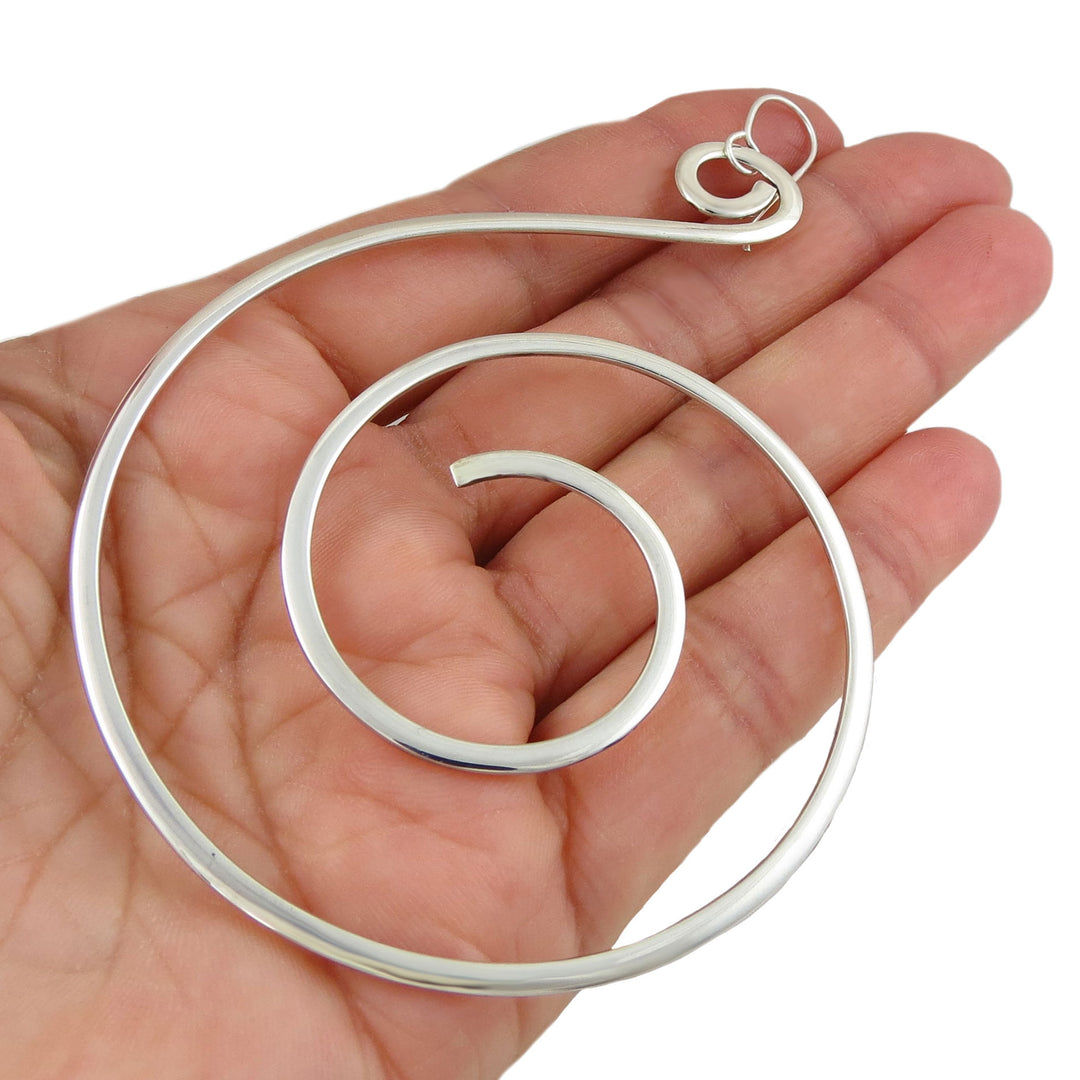 Sterling 925 silver spiral hoop earring held in a hand against a white background