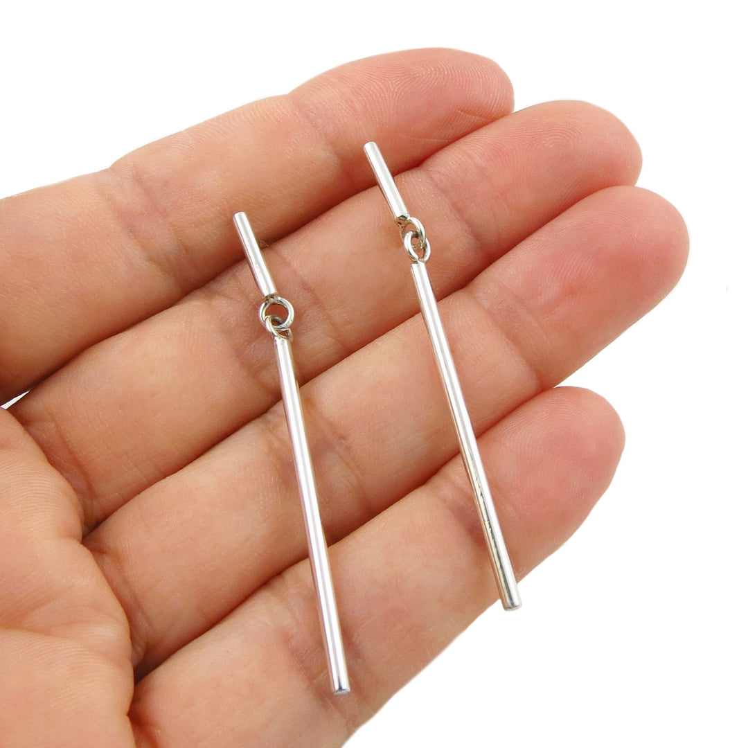 Two solid 925 sterling silver drop earrings with straight bar drops and small circular links, shown resting on an open hand against a white background.