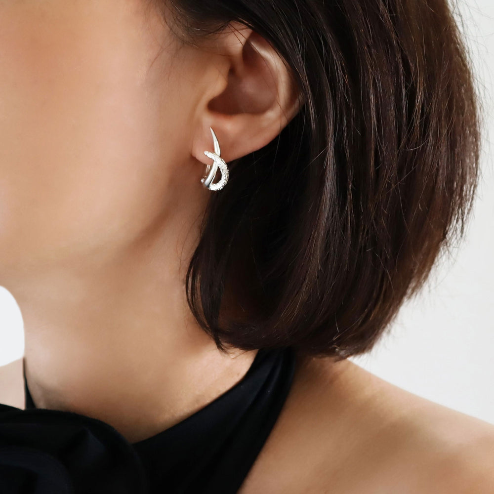 Long spiked 925 sterling silver sculpted huggie style hoop earring worn by a woman with dark hair