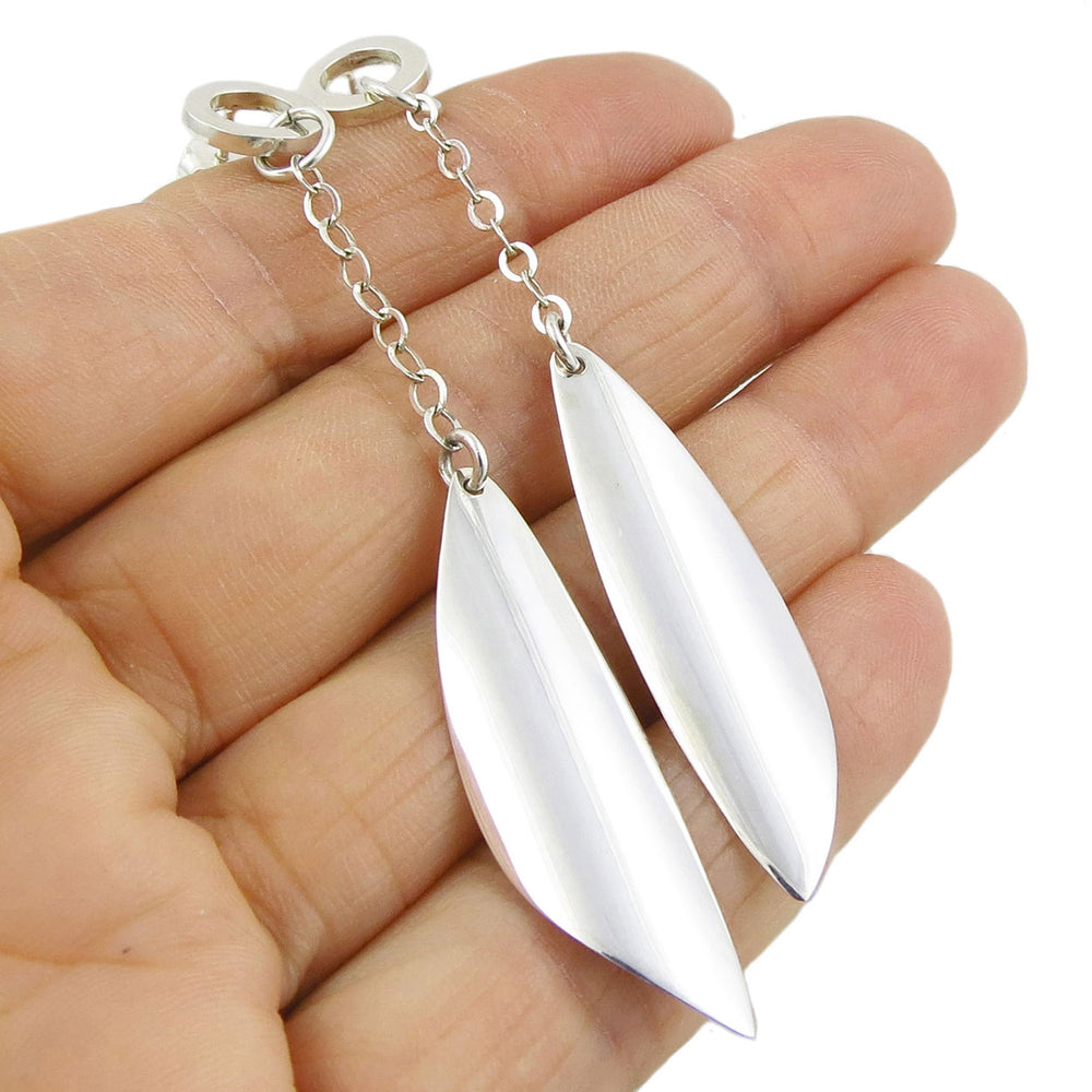 Long curved silver drops with chains ladies earrings held in a person's hand