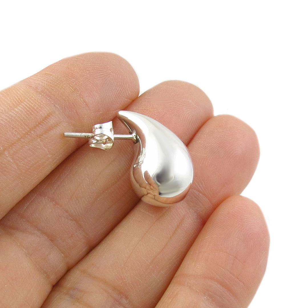 A single 925 sterling silver teardrop stud earring for women held between fingers on a white background