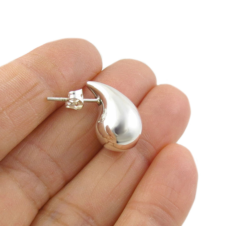 A single 925 sterling silver teardrop stud earring for women held between fingers on a white background