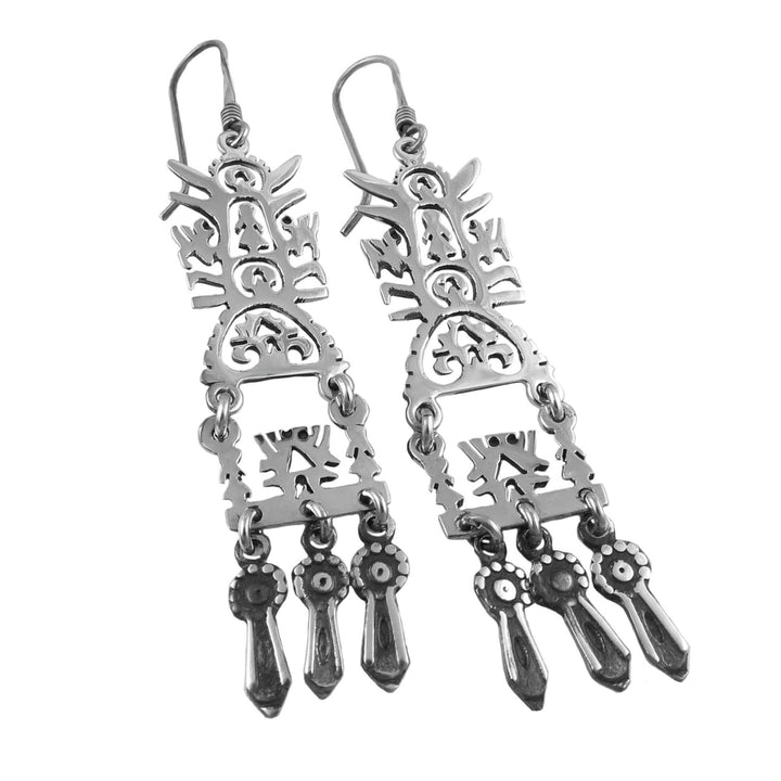 A pair of mexican 925 sterling silver dangling drop earrings with intricate tree of life motifs on a white background