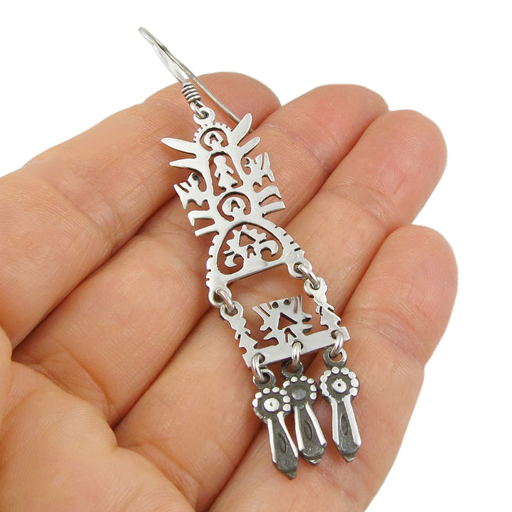 925 sterling Silver decorative tree of life handmade mexican earring held in a hand against a white background