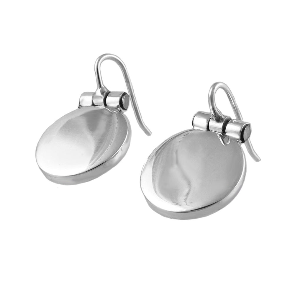 A pair of silver earrings with oval drops attached to hinged hooks on a white background. 