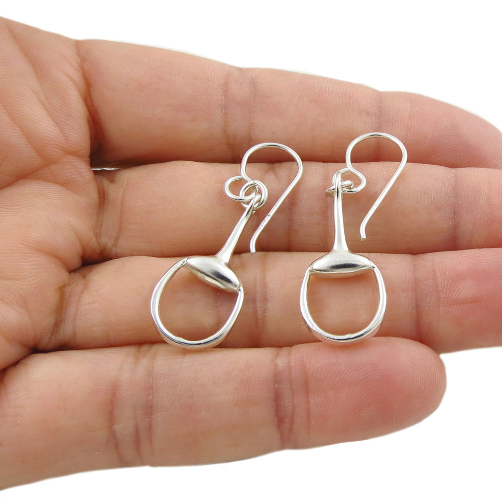 Solid ladies 925 silver dangling hook horse snffle bit earrings held in a hand on a white background