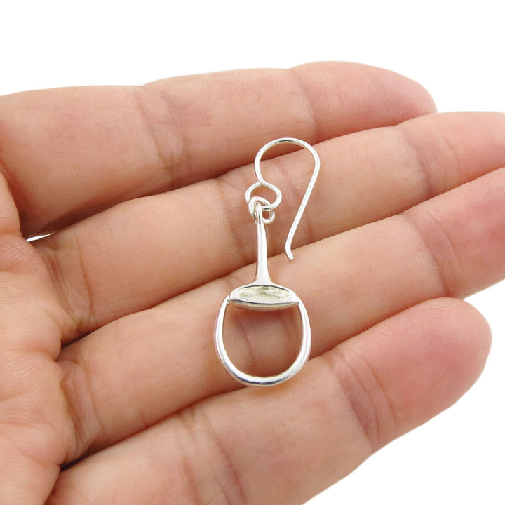Solid 925 Silver horse snaffle bit hook earring held between fingers on a white background