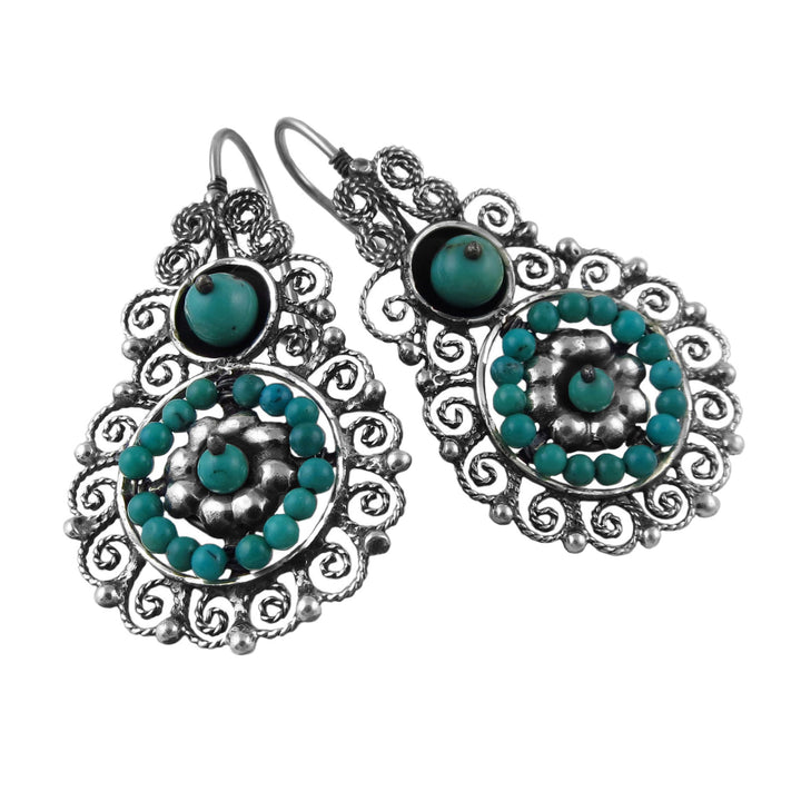 Pair of silver earrings with turquoise gemstones on a white background