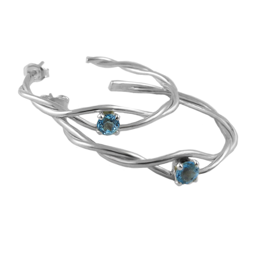 Silver hoop earringss with blue topaz gemstones on a white background
