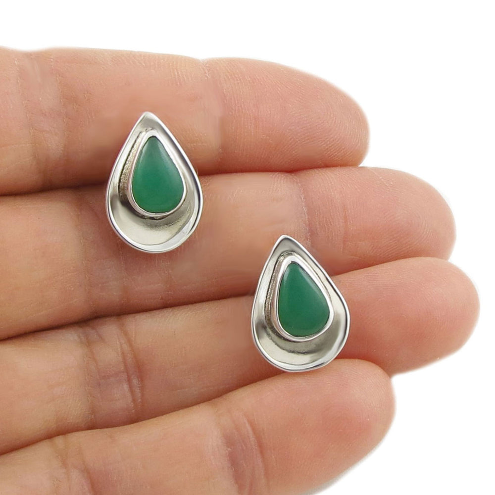 Teardrop-shaped earrings with green stones and silver borders on a hand.