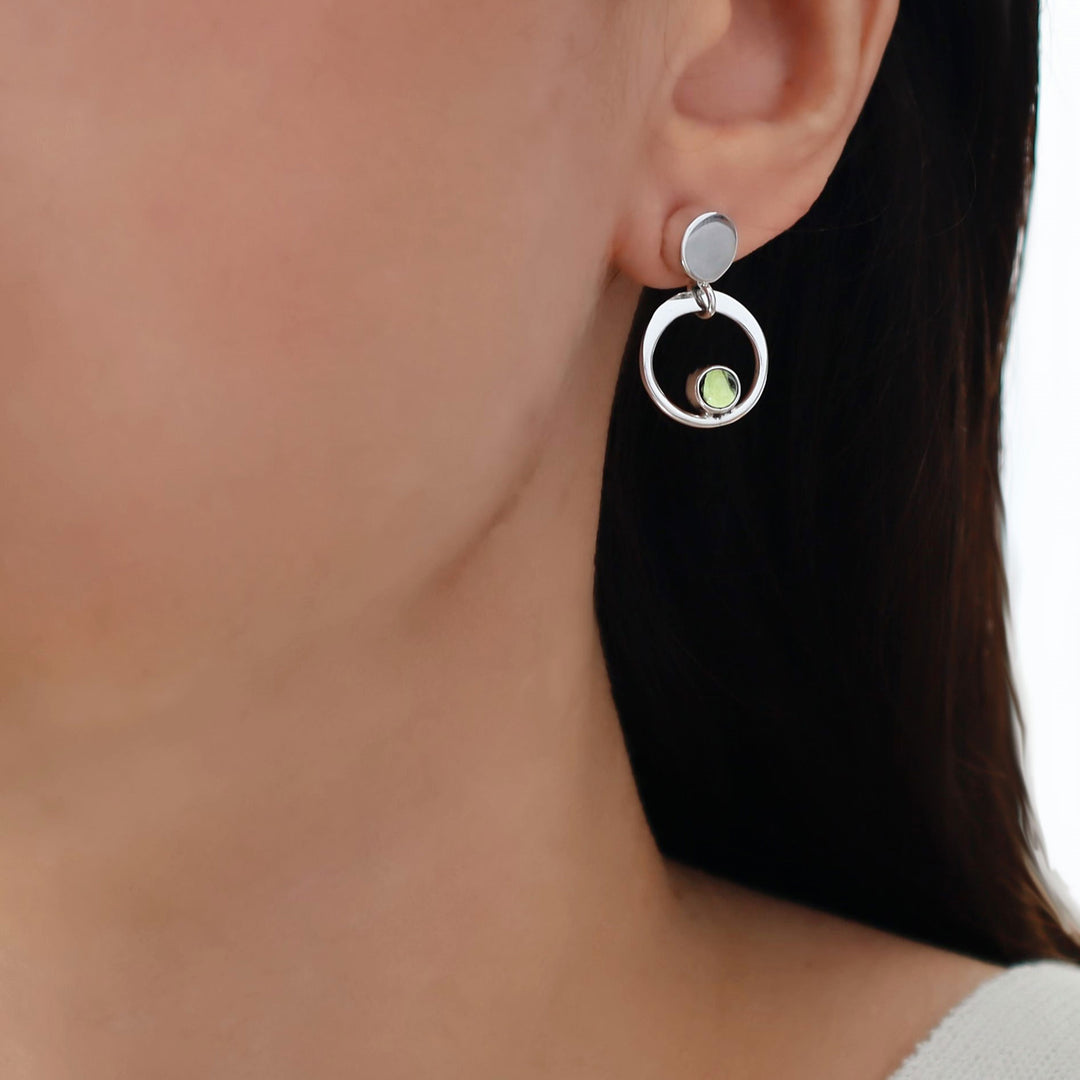 Earring with a green peridot gemstone on a blurred background