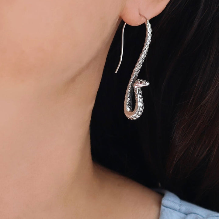 Silver snake-shaped earring worn by a person with dark hair.