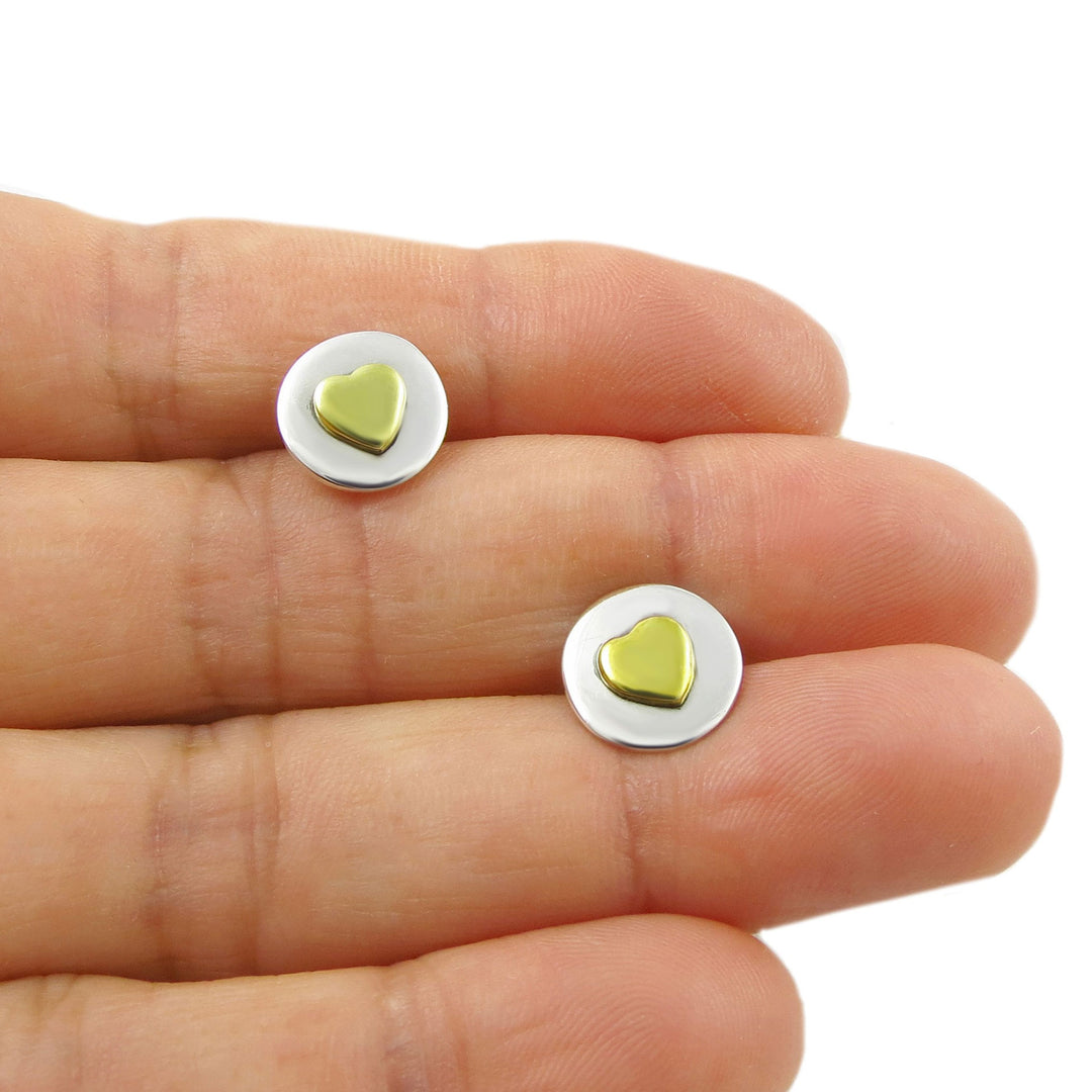 Gold heart-shaped earrings on a hand with a white background