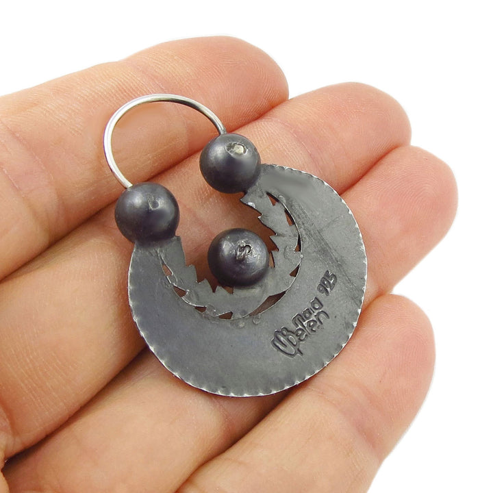 925 sterling Silver creole earring with a large oval shape and a blackened ntiqued finish held in a hand against a white background