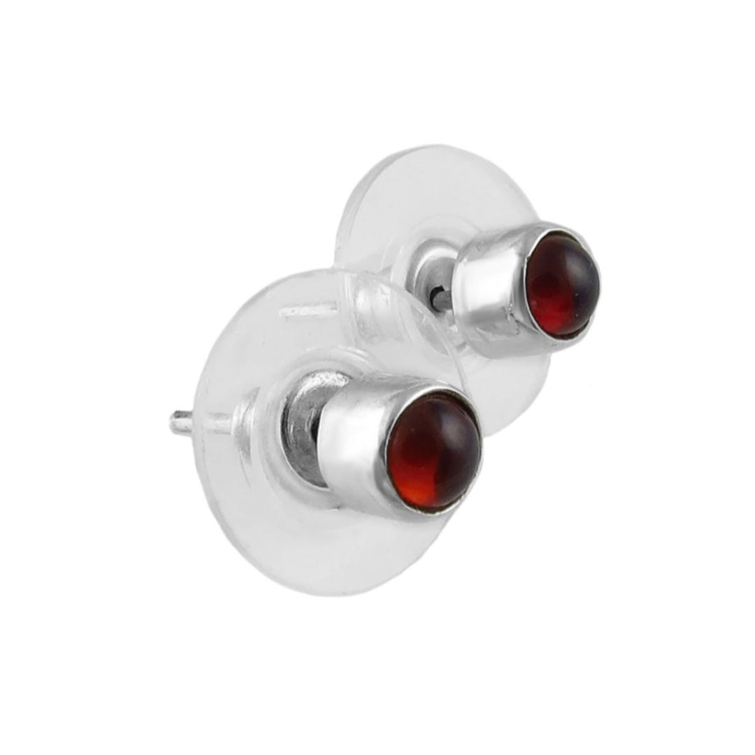 Silver earrings with red garnet gemstones on a white background