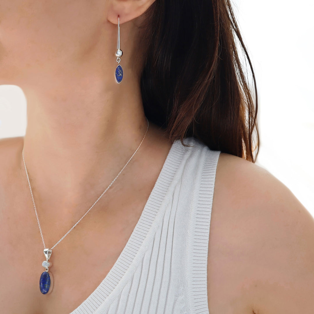 Close-up of a woman wearing a silver necklace and earrings with blue lapis lazuli stones on a white background