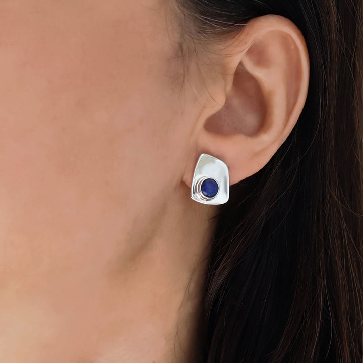 Silver earring with a blue lapis lazuli gemstone worn by a woman