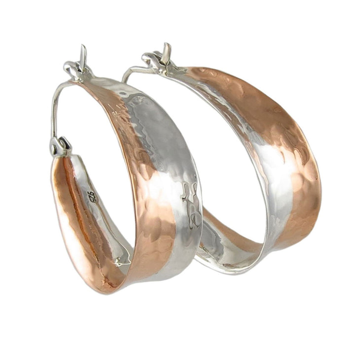 Large teardrop hoop earrings in copper and silver with a hammered finish.