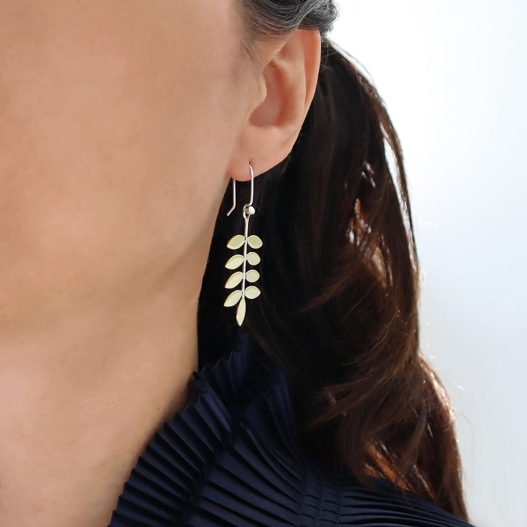 Close-up of a person wearing a leaf-shaped earring with a blurred background