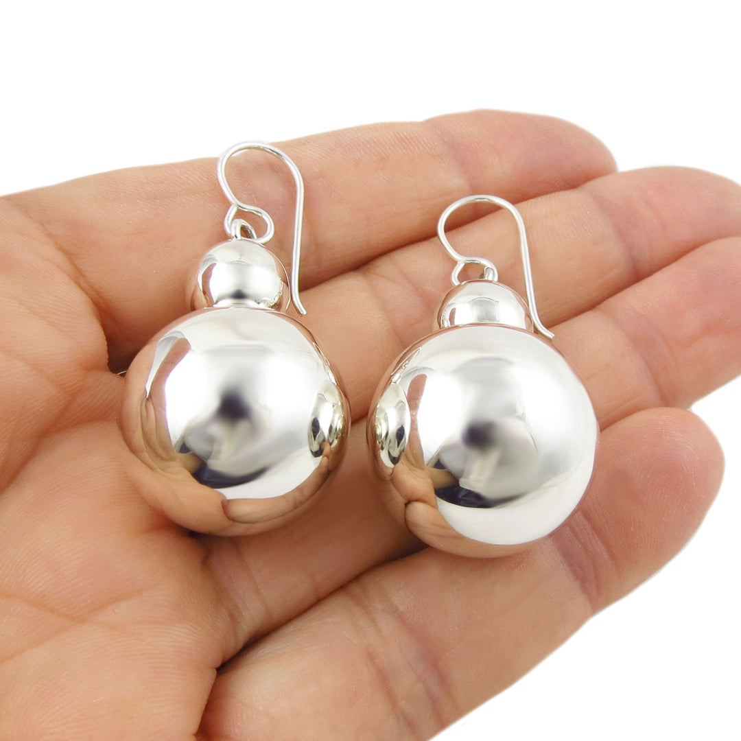 Large polished 925 sterling silver double ball bead earrings held in a hand against a white background