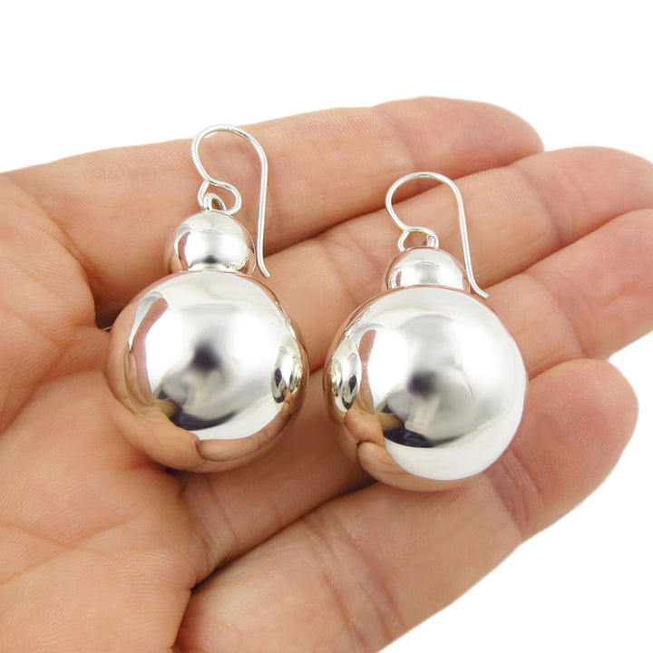 Large polished 925 sterling silver double ball bead earrings held in a hand against a white background