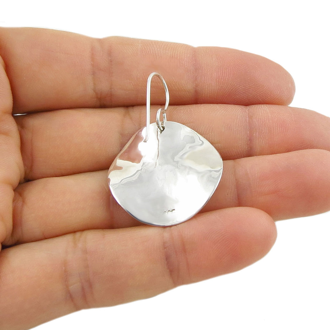 Round 925 silver earring held upside down in a hand against a white background