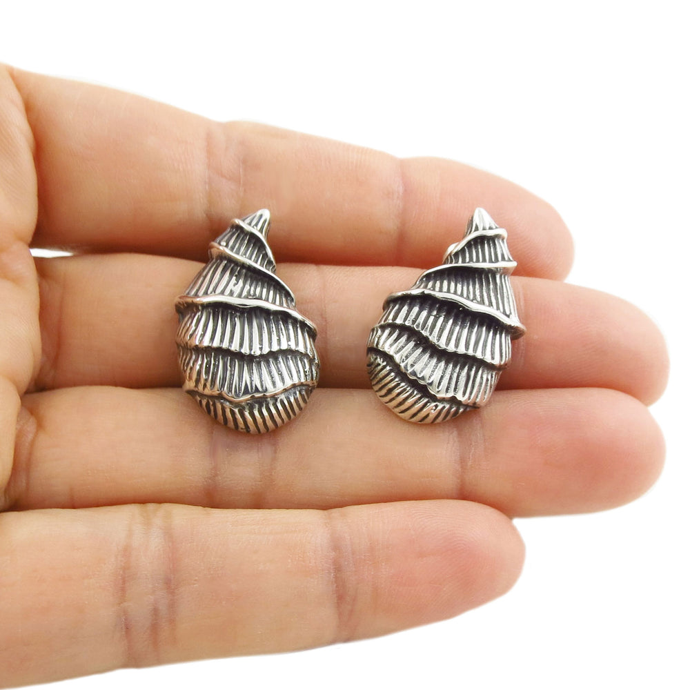 Large Mexican sterling 925 silver mollusc shell earrings held in a person's hand on a white backgroud. 