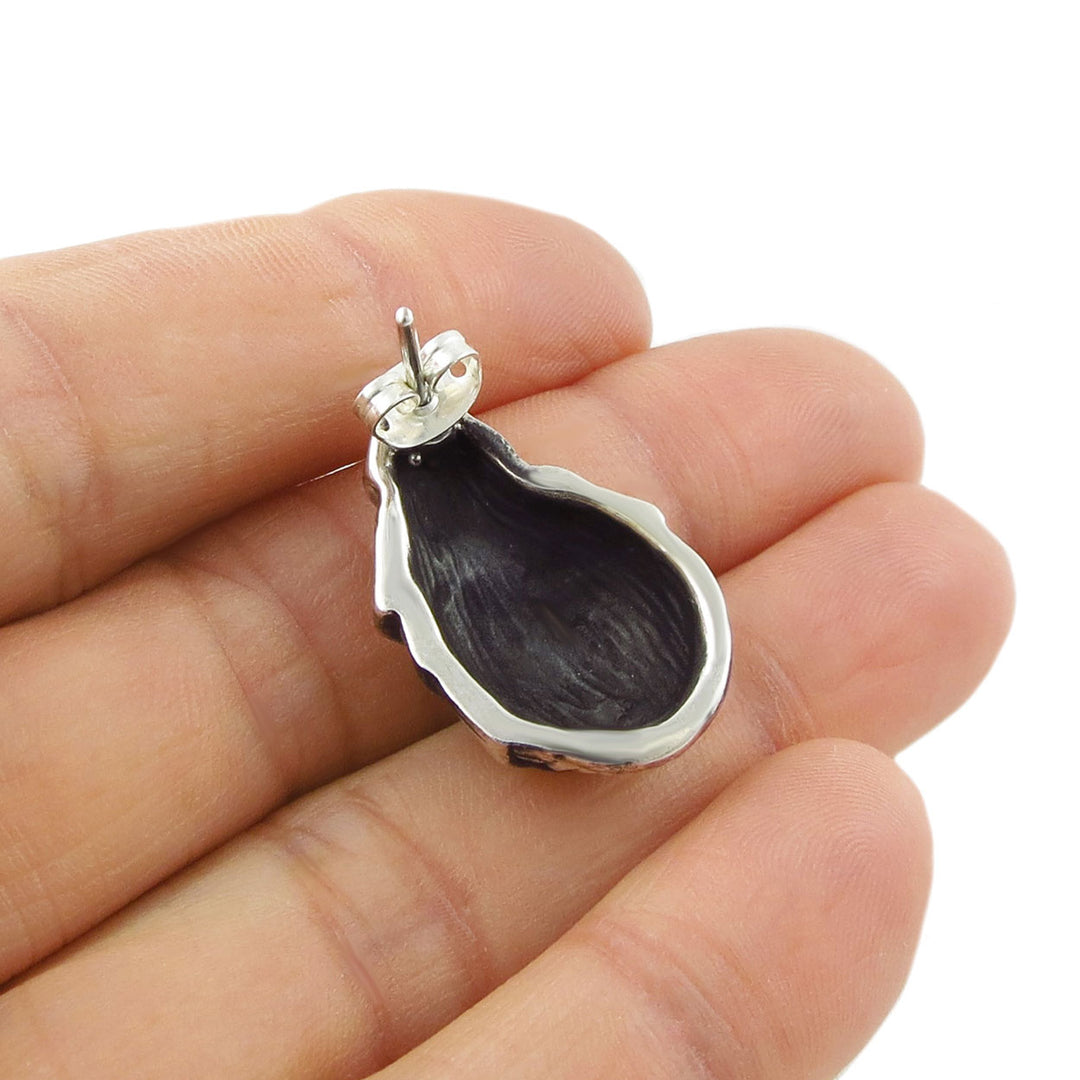 Underside of a 925 sterling silver shell earring showing the space inside - held in a hand against a white background