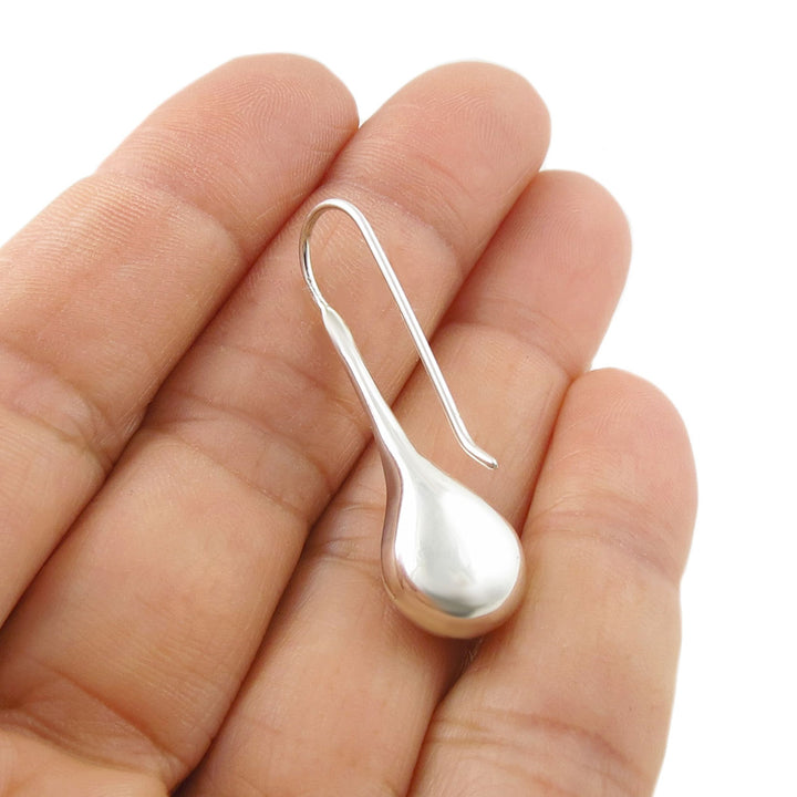 925 Silver teardrop earring for women held between fingers on a white background