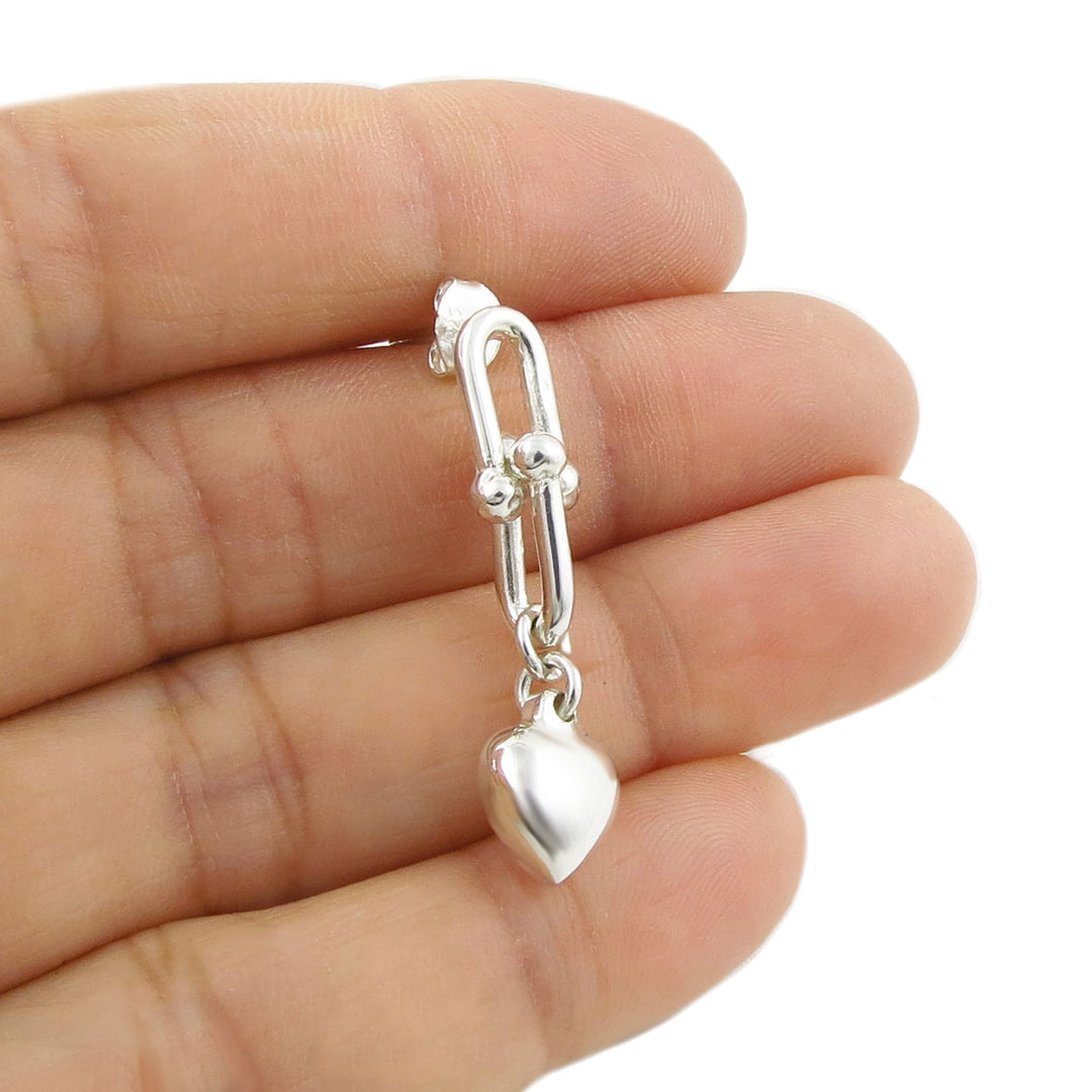 925 sterling silver gauge link chain and heart-shaped charm earring held between fingers against a white background