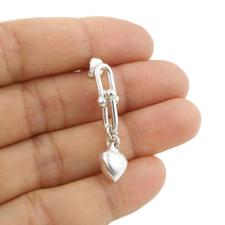 925 sterling silver gauge link chain and heart-shaped charm earring held between fingers against a white background