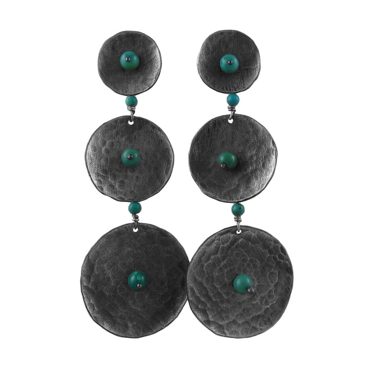 A bold pair of chandelier drop earrings featuring triple discs with a matt black industrial and turquoise beads on a white background