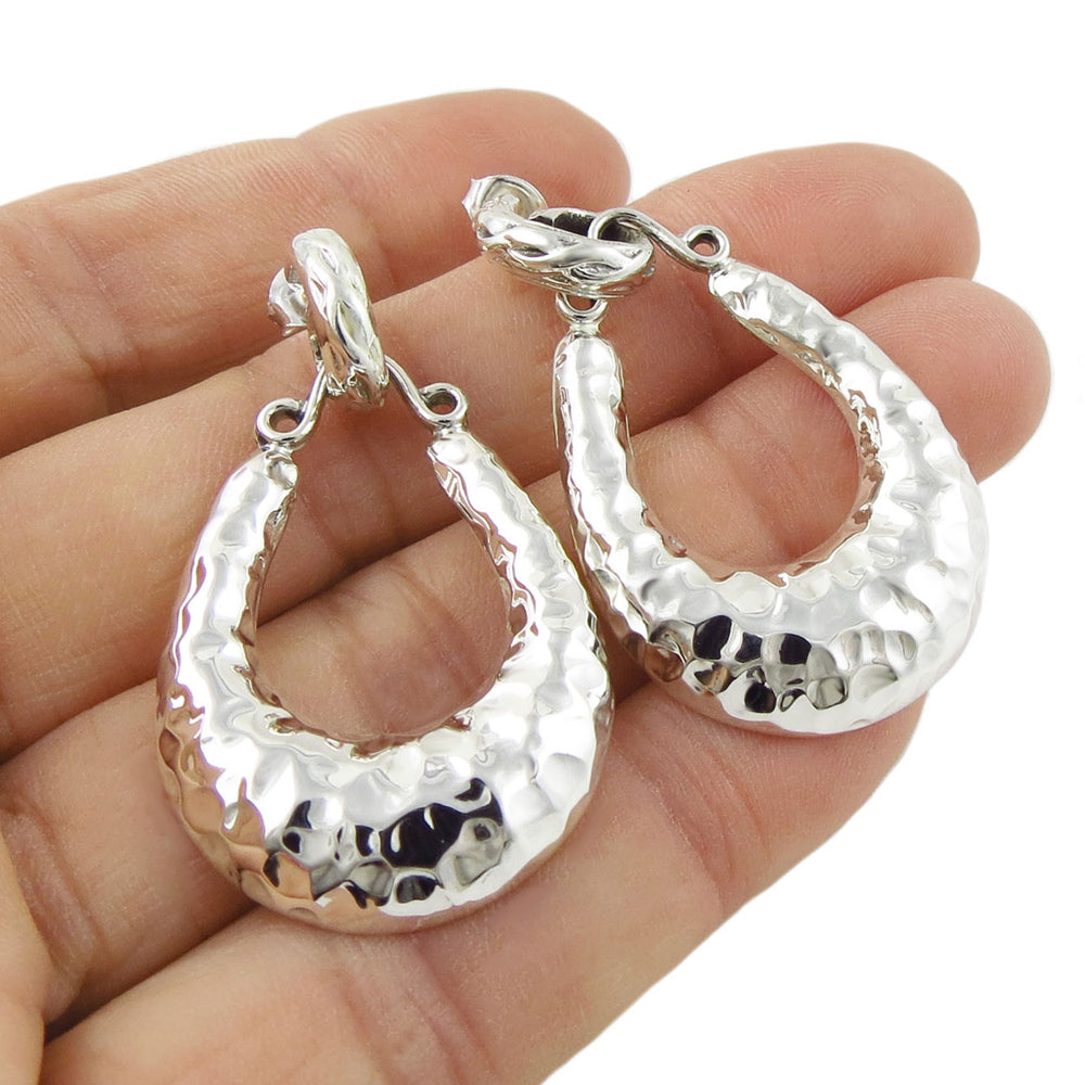 Large hammered 925 sterling silver Mexican gypsy hoop earrings held in a hand against a white background