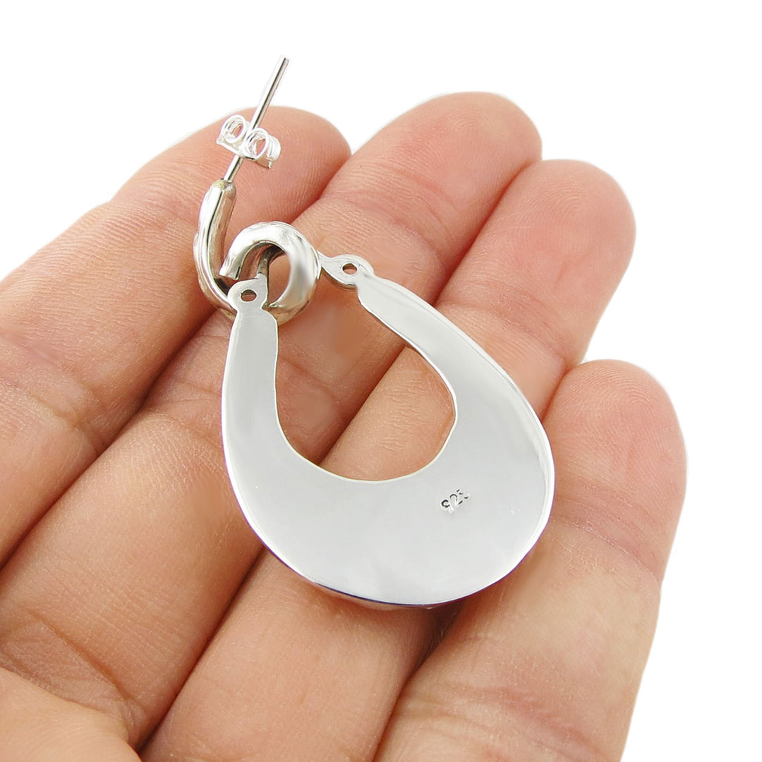 The reverse of large drop earring in 925 sterling silver held in a person's hand