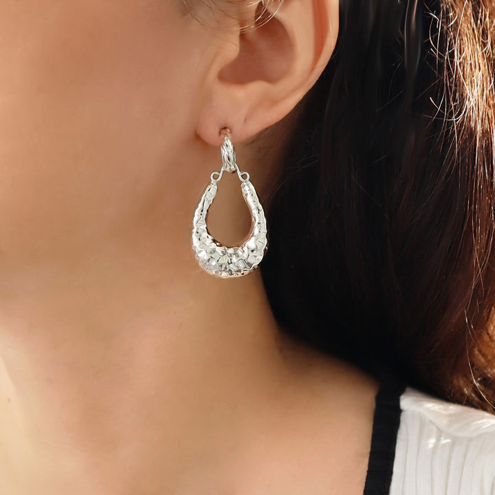 Large dangling hammered 925 sterling silver gypsy style unique hoop earring worn by a woman with dark hair.