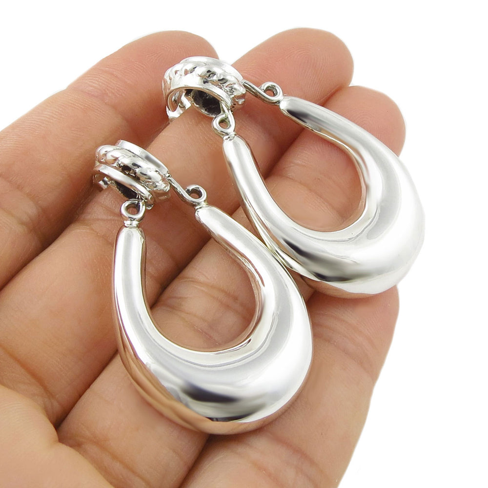 Large gypsy style 925 sterling silver Taxco hoop earrings held in a person's hand. 