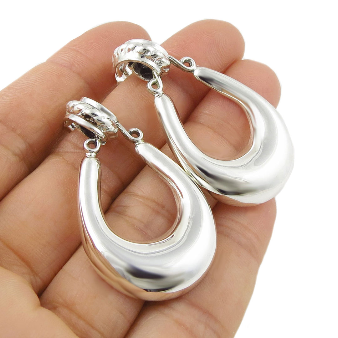 Large gypsy style 925 sterling silver Taxco hoop earrings held in a person's hand. 