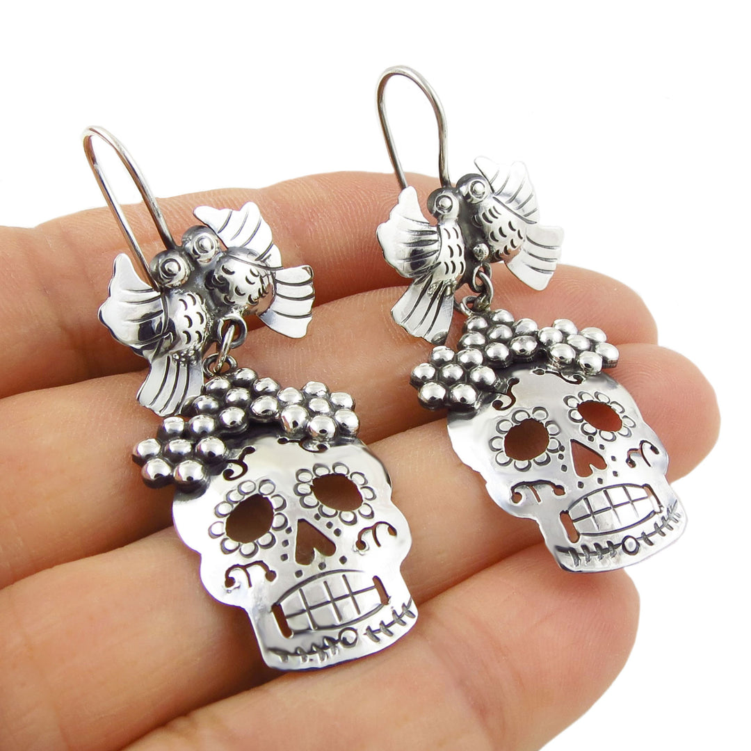 Sterling 925 Silver Mexican day of the dead sugar skull earrings held in a hand against a white background