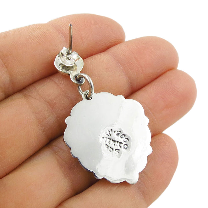 The reverse of a large 925 silver earring  held in a hand on a white background