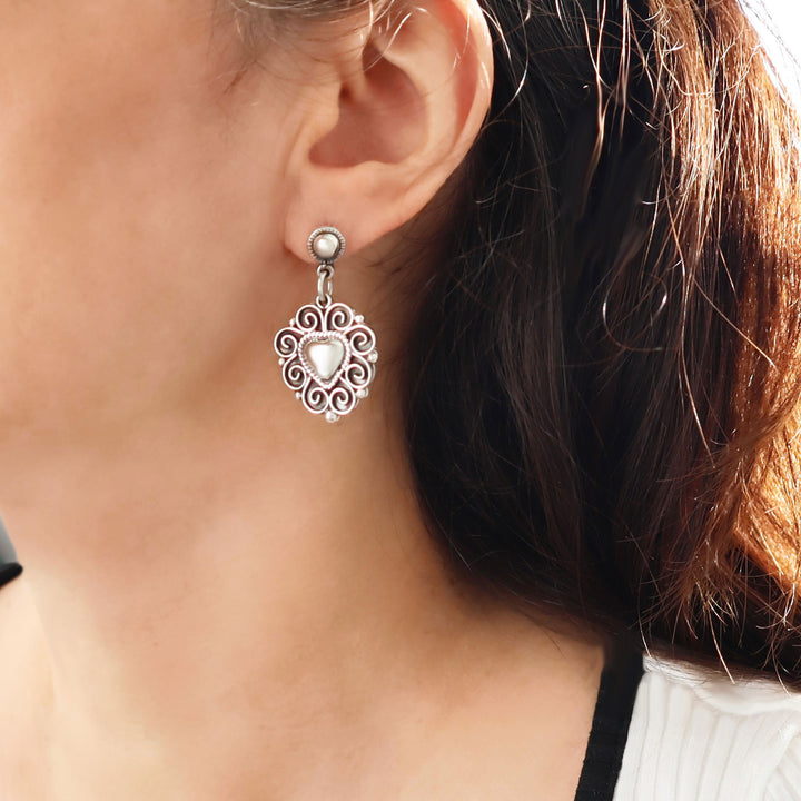 Close-up of a woman wearing a large Taxco 925 sterling silver earring with a heart design.