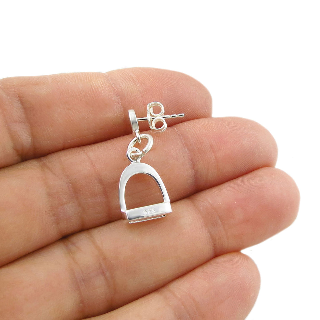 A single 925 terling silver horse stirrup earring with a post fastener held in a person's hand. 