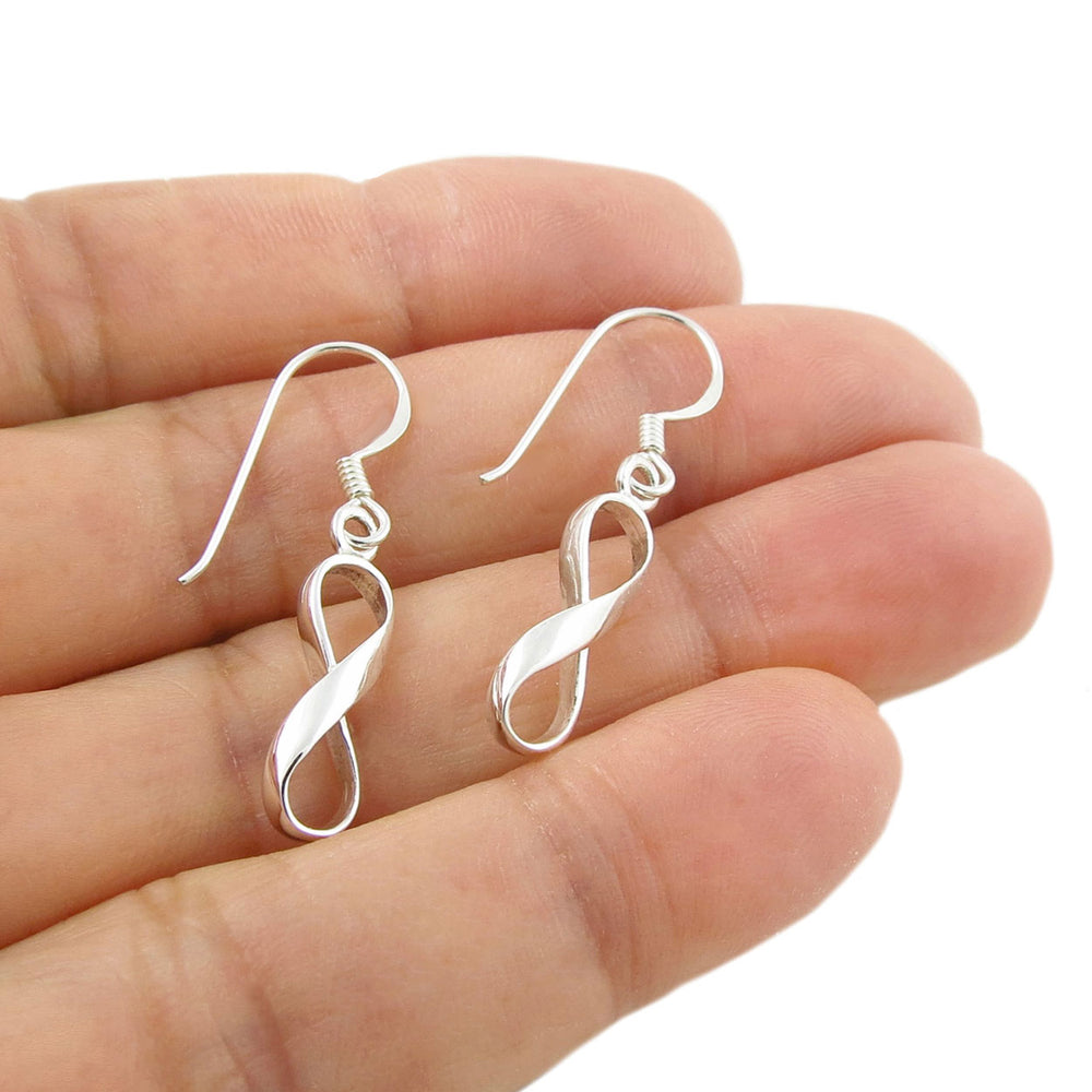 Long dangling infinity sterling silver earrings held in a person's hand