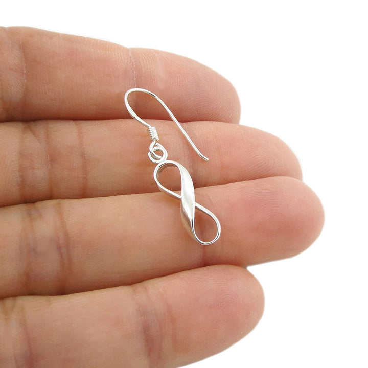 925 sterling silver infinity-shaped earring held between fingers on a white background