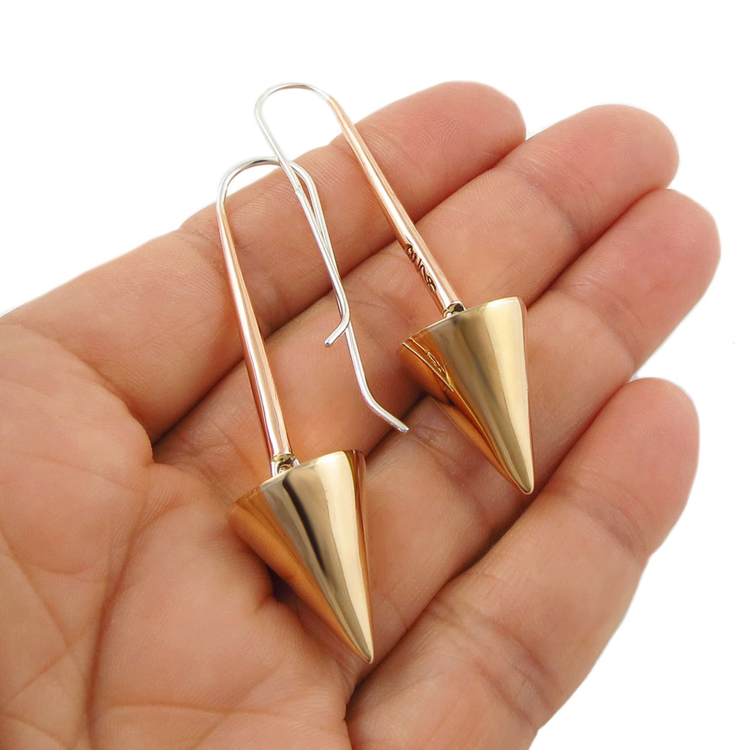 Long mixed metal 925 silver and copper dangling geometric threader earrings held in a hand against a white background