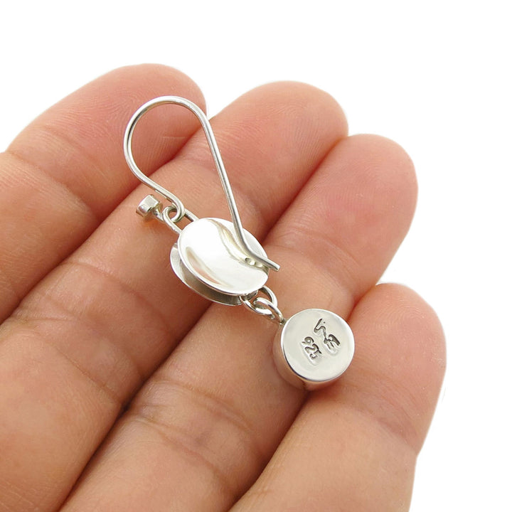 Reverse of a 925 silver earring held between fingers on a white background to show the 925 hallmark