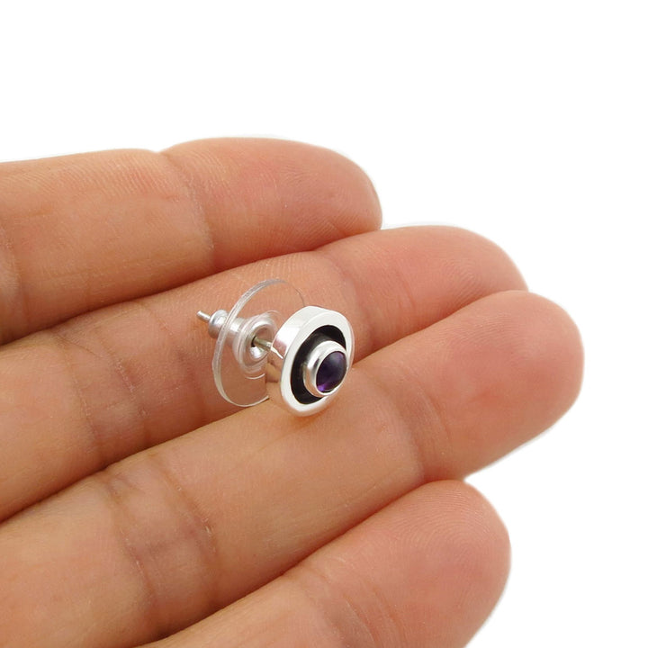 Sterling 925 Silver women's stud earring with a purple amethyst gemstone held between fingers on a white background
