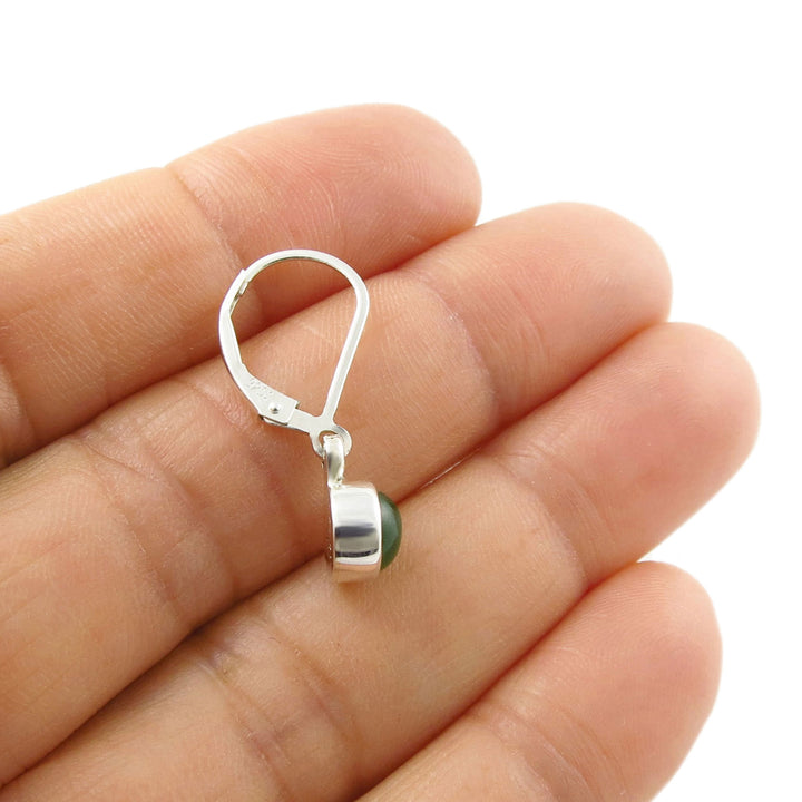 Sterling 925 silver dangling earring with a green jade gemstone held between a woman's fingers on a white background
