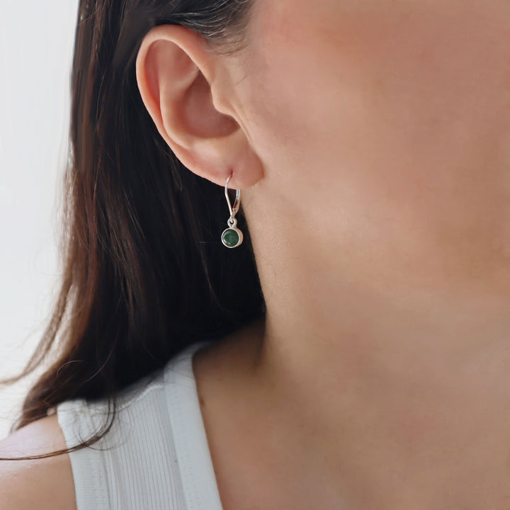 Close-up of a woman wearing a green  jade gemstone earring with lever back hooks.