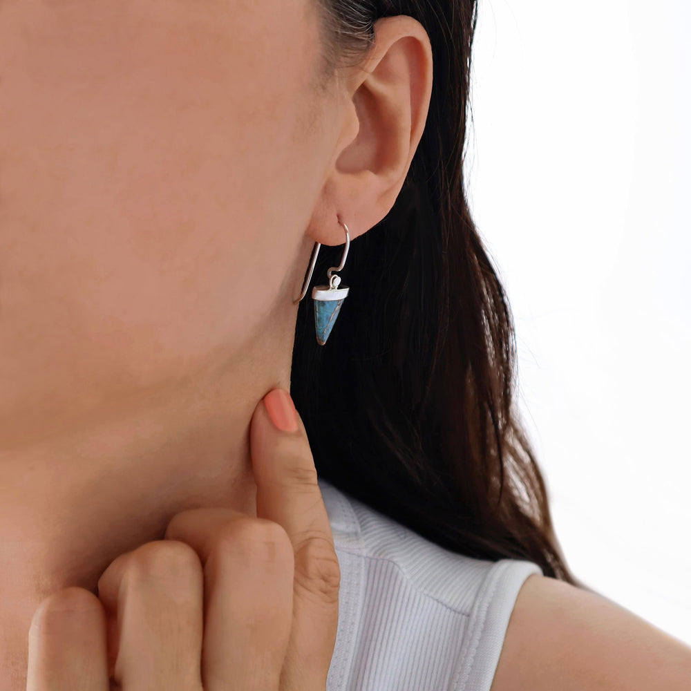 Close-up of a woman wearing a unique 925 sterling silver earring with a large pointed turquoise gemstone.