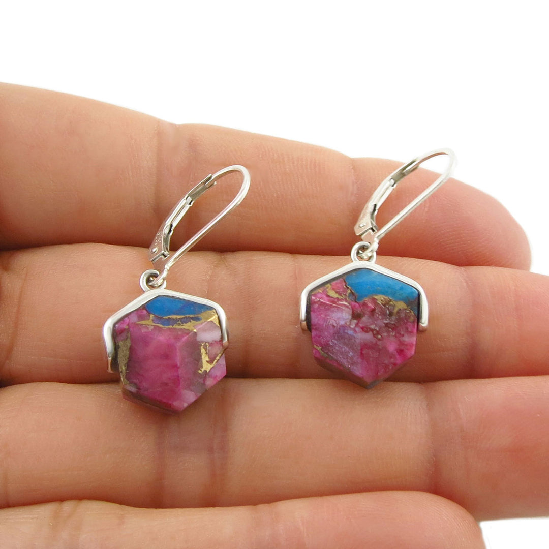 Sterling 925 Silver earrings with pink and blue purple spiny shell held between fingers on a white background